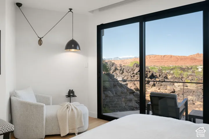 Large sliding glass doors accessing an outdoor area, mountain scenery, light wood-finish flooring, and a unique pulley lighting fixture