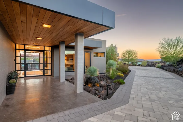 Paver driveway leading to a covered entrance with a wood-finish ceiling