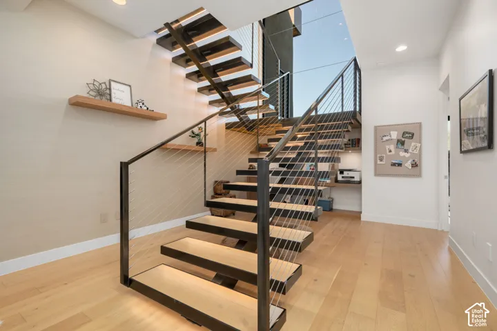 Floating staircase with wood-finish treads and metal cable railing