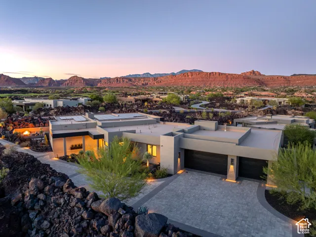 Modern exterior with a flat roofline, integrated two-car garage, paved driveway, and desert landscaping