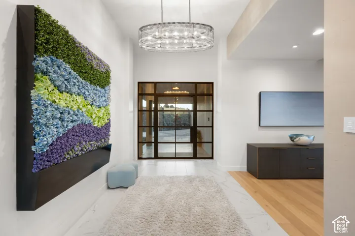 Entryway featuring a decorative wall-mounted botanical art piece, a contemporary chandelier, and large paneled glass doors