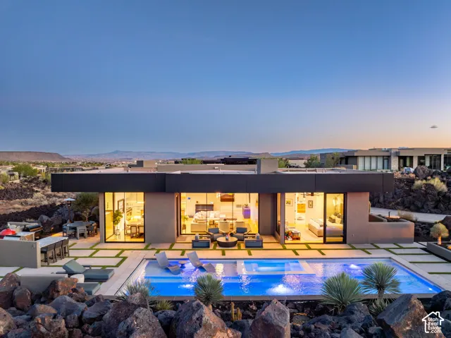 Modern exterior with a flat roofline, floor-to-ceiling windows, and a rectangular swimming pool with integrated lighting
