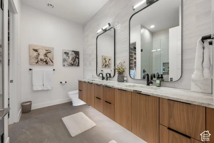 Dual floating vanities with wood-finish cabinetry, black hardware, and stone countertops