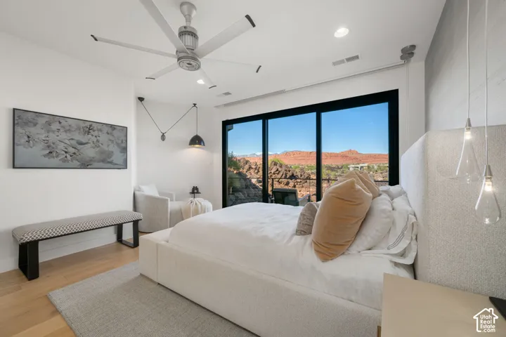 Full-height sliding glass door, ceiling fan, recessed lighting, wood-finish flooring, and pendant lighting