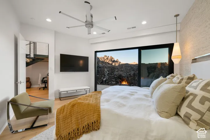 Expansive sliding glass door, recessed lighting, ceiling fan, and wood-finish flooring