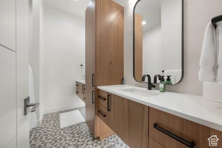 Wood-finish floating vanity with integrated sink, white countertop, and matte black faucet