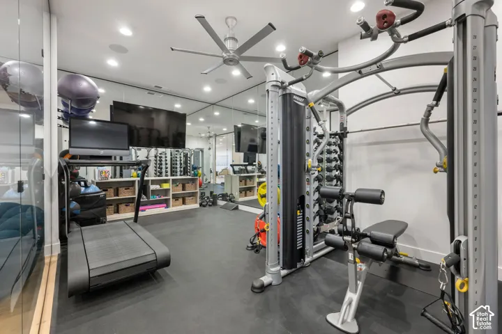 Dedicated fitness room featuring rubber flooring, recessed lighting, ceiling fan, and mirrored wall