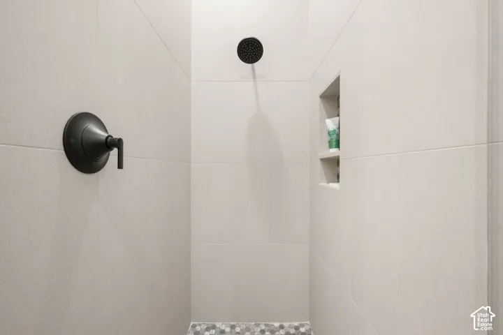Tiled shower with matte black fixtures, built-in storage niche, and mosaic tile flooring