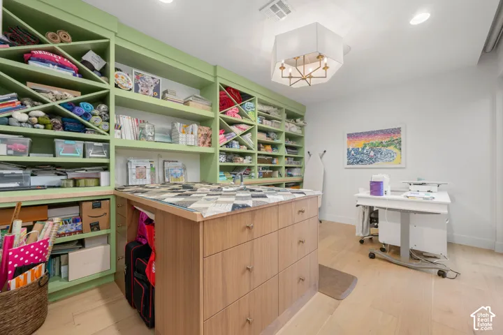 Custom built-in shelving with integrated work surface, central wood-finish island with multiple drawers, light-toned wood-finish flooring, and recessed lighting
