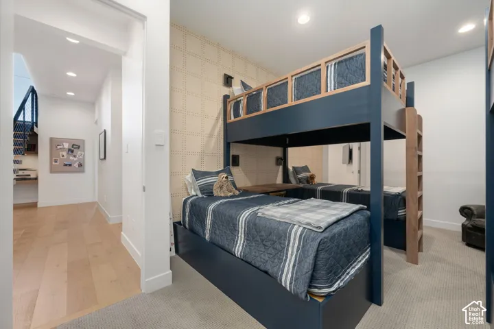 Carpeted bedroom featuring built-in bunk beds with integrated ladders, recessed lighting, and an accent wall