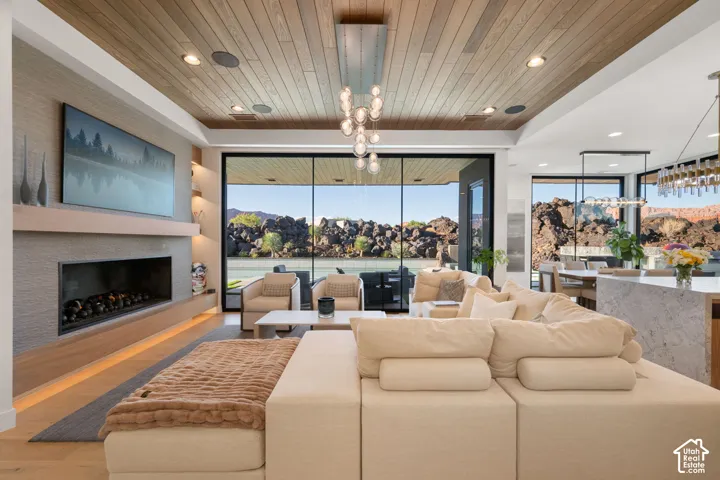 Wood-finish ceiling panels, linear fireplace with stone surround, large format sliding glass doors, built-in shelving, and recessed lighting