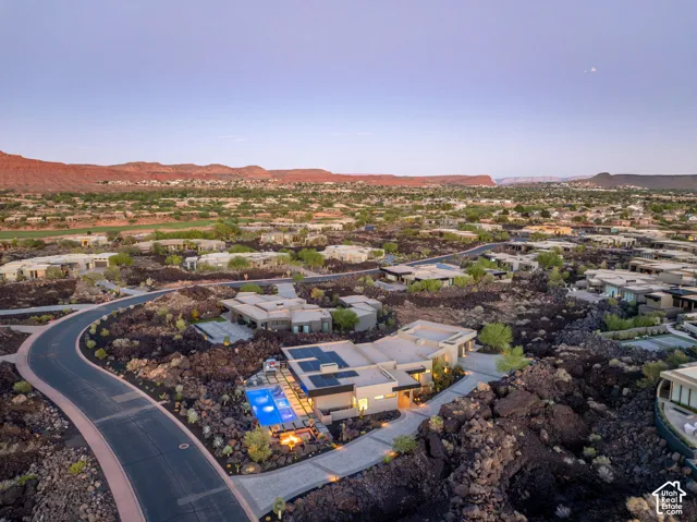 Modern-style property with a swimming pool, integrated solar panels, and a fire pit, set within a desert landscape