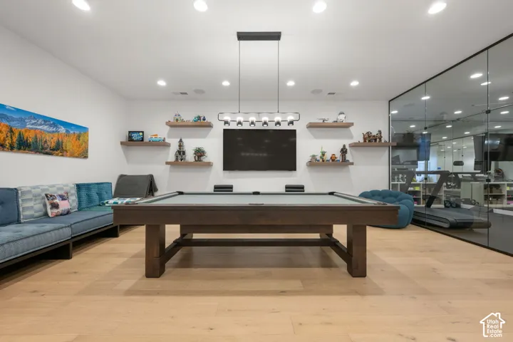Recessed lighting, wood-finish flooring, glass wall partition, built-in shelving, and a modern pendant light fixture
