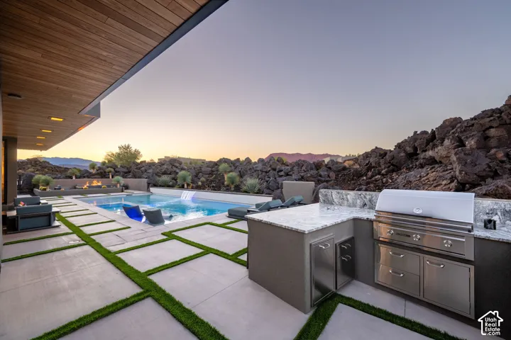 Outdoor kitchen with granite countertops, stainless steel appliances, and built-in cabinetry