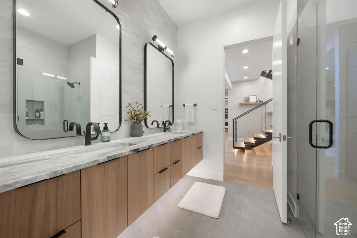 Floating double vanity with wood-finish cabinetry, stone countertop, and two framed mirrors