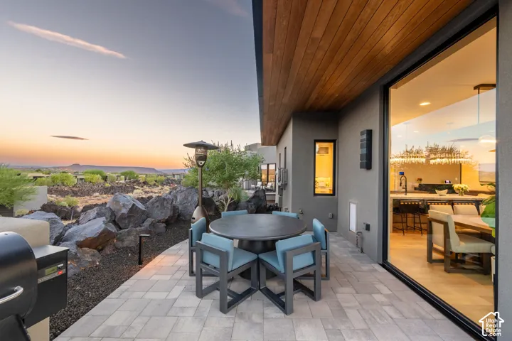 Expansive outdoor patio with paver flooring, wood-finish ceiling, and large glass sliding doors