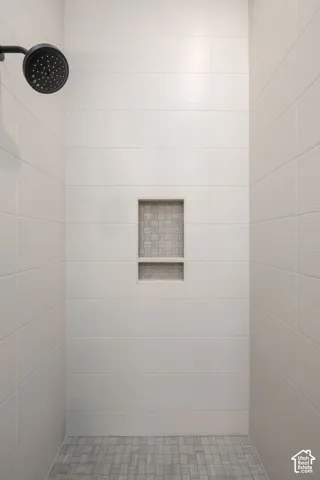 Shower with matte black showerhead, large format wall tiles, and mosaic tile shower niche
