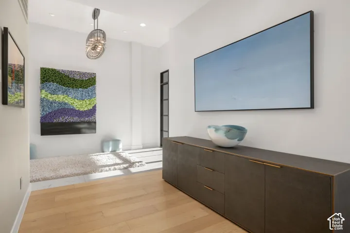 Hardwood flooring, recessed lighting, and a contemporary pendant light fixture