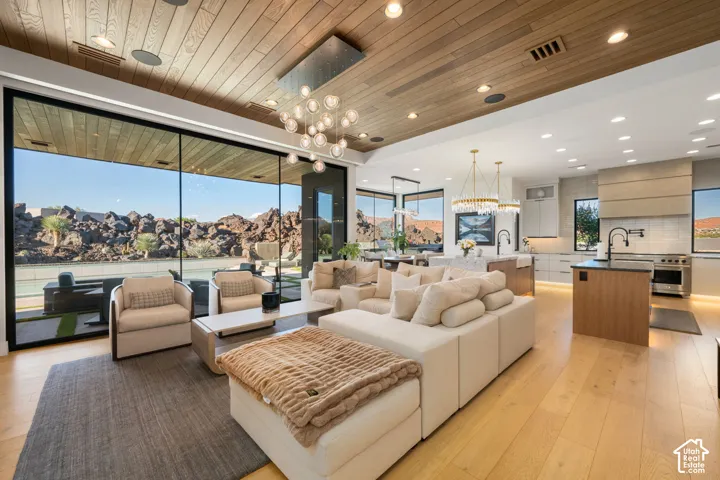 Expansive wall of windows, wood-finish flooring, wood-paneled ceiling, recessed lighting, and two kitchen islands with integrated sinks