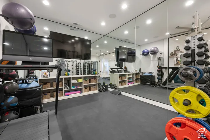 Dedicated fitness room featuring wall-to-wall mirrors and recessed lighting