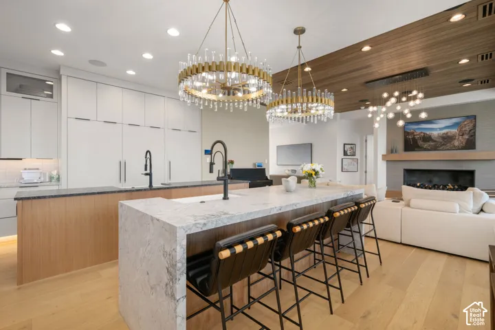 Kitchen featuring two islands with stone countertops, integrated appliances, wood-finish flooring, and decorative chandeliers