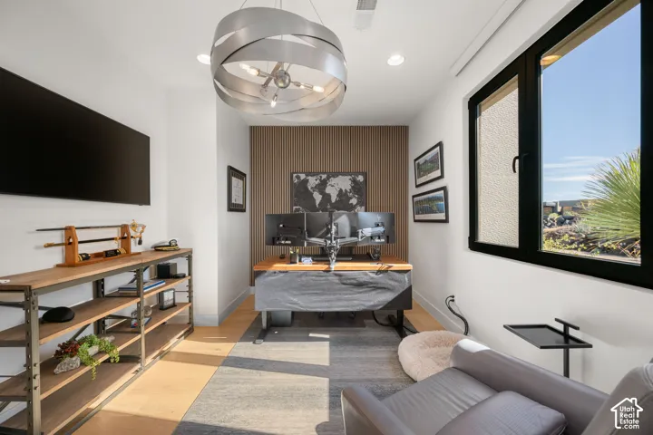 Wood-finish flooring, accent wall with vertical wood paneling, contemporary chandelier, recessed lighting, and a dark-framed window