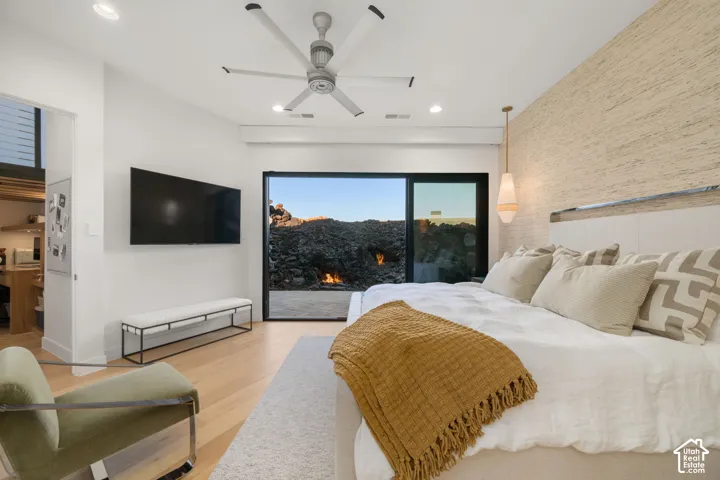 Vaulted ceiling with recessed lighting and ceiling fan, wood-finish flooring, sliding glass door, and accent wall with textured finish
