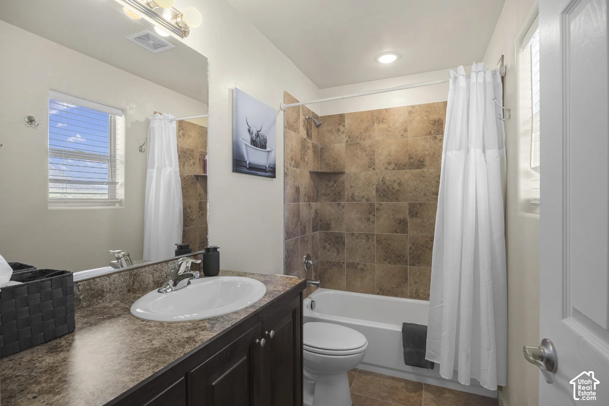 Bathroom featuring a vanity with an integrated sink, a large mirror, and a shower-over-tub combination with tiled surround