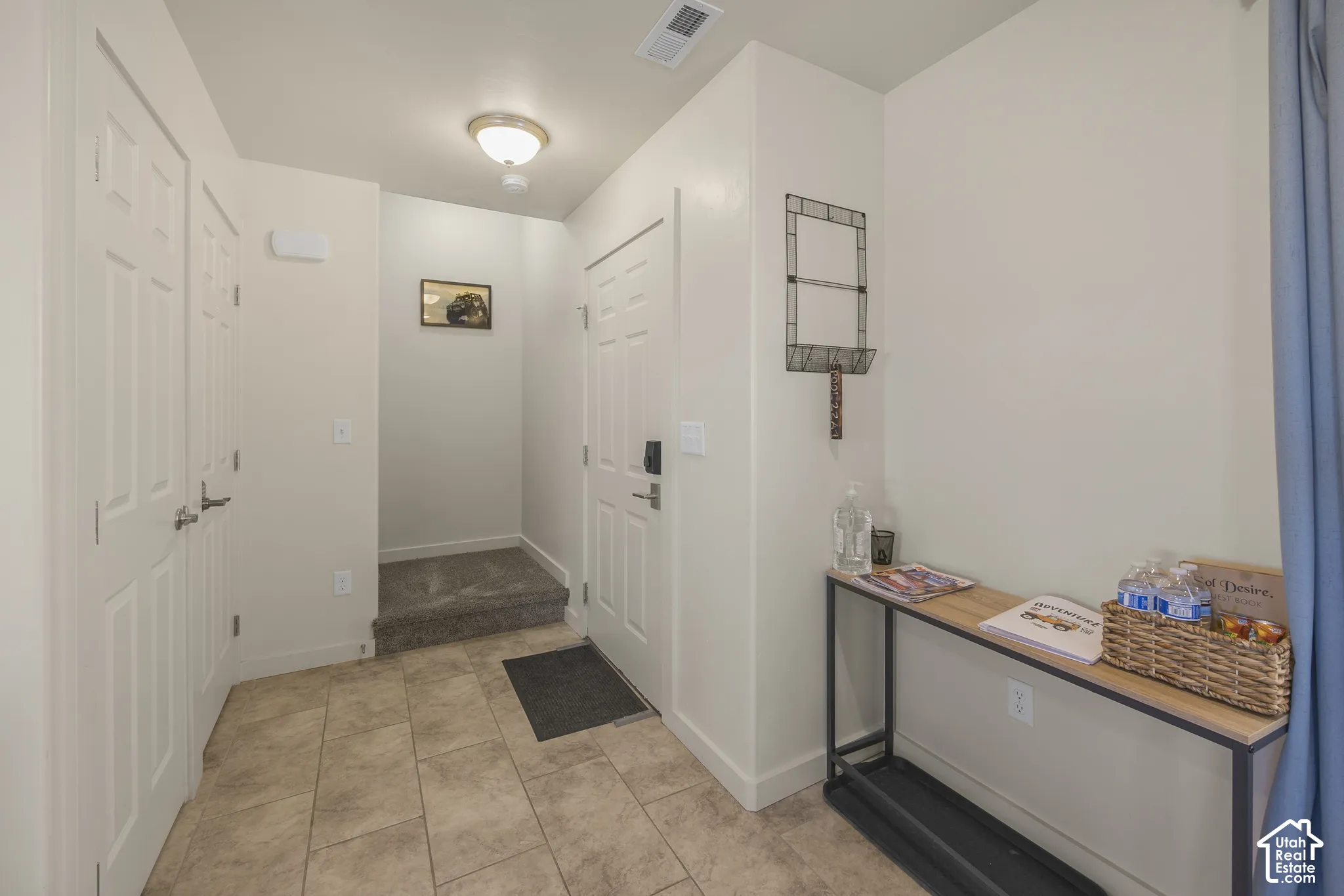 Tiled entryway flooring with a built-in step, dual panel doors, and flush-mount lighting