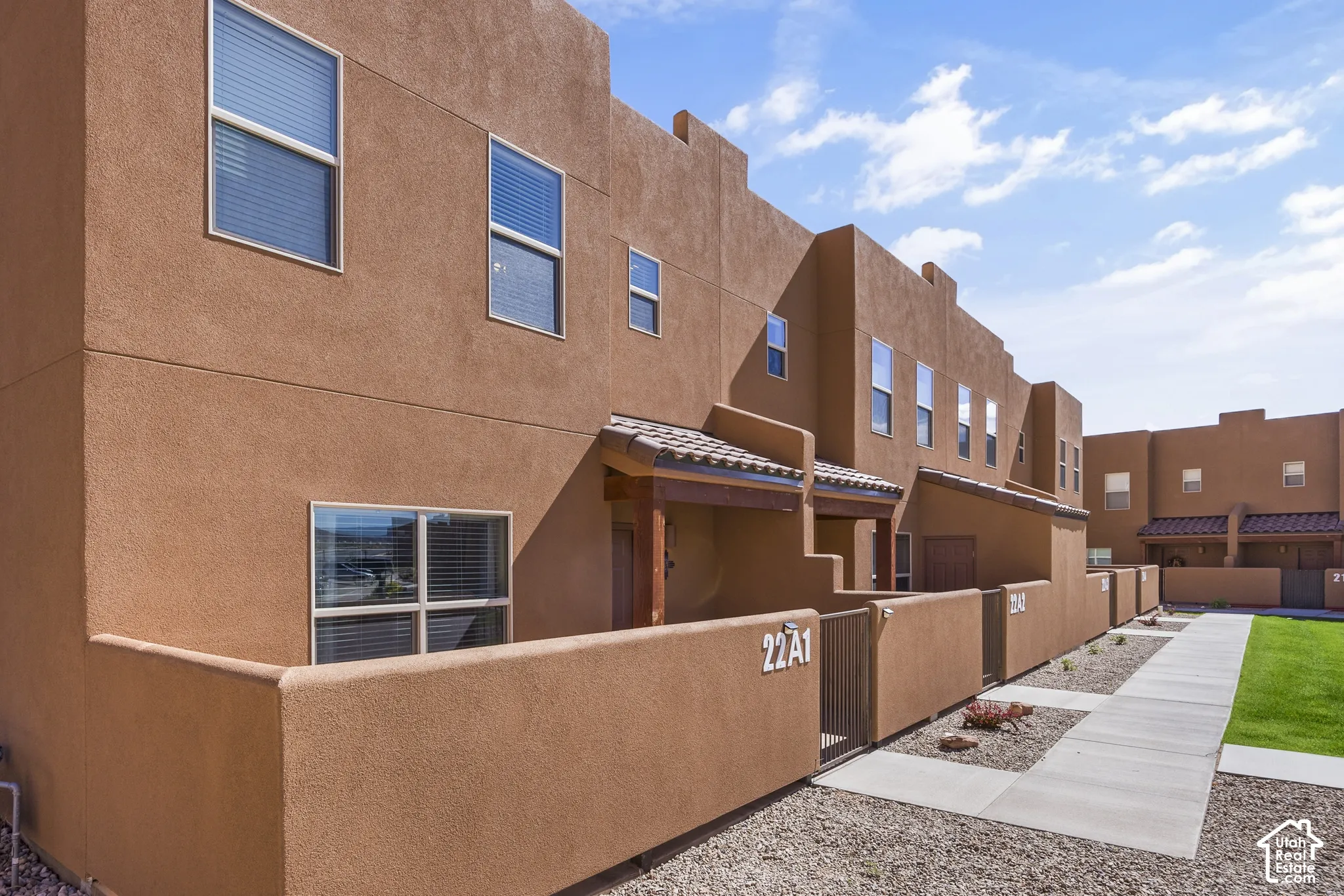 Stucco exterior with multiple windows, covered entry, and tile roof accents
