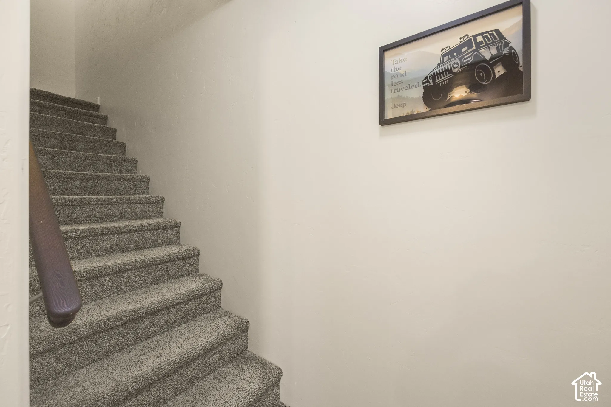 Carpeted staircase with a wood handrail