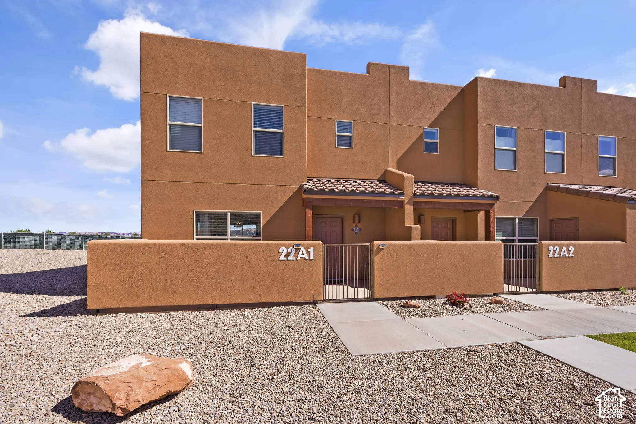 Stucco exterior with multiple windows, covered entryways, and terracotta tile roofing