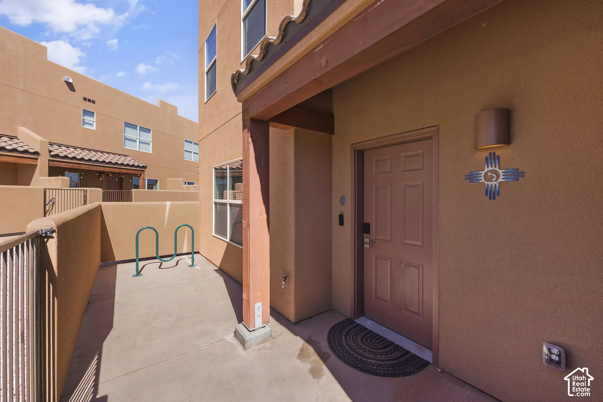 Stucco exterior with a paneled entry door, porch light, and an adjacent decorative wall sconce