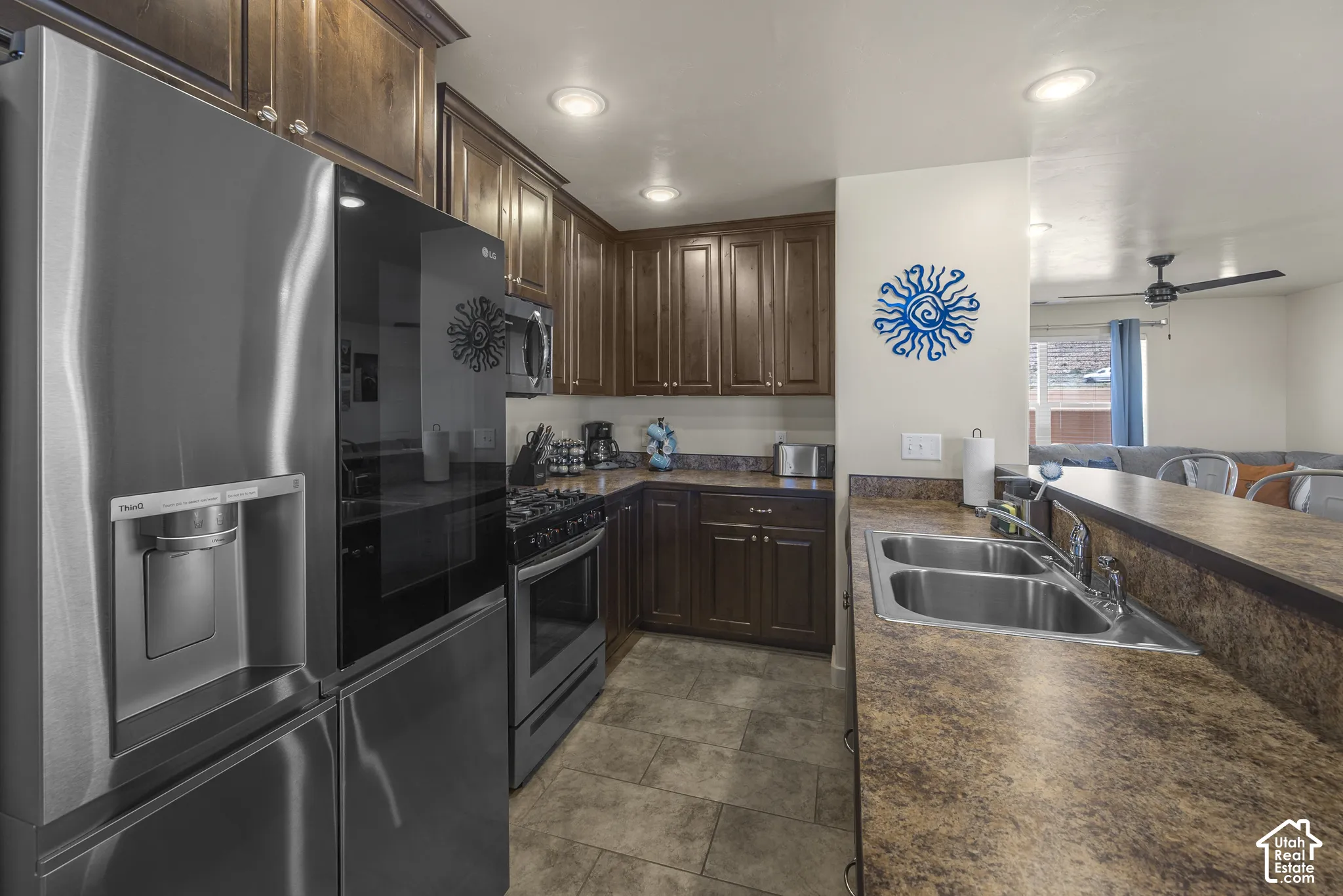 Kitchen featuring stainless steel appliances, wood cabinetry, composite countertops, and a double basin sink