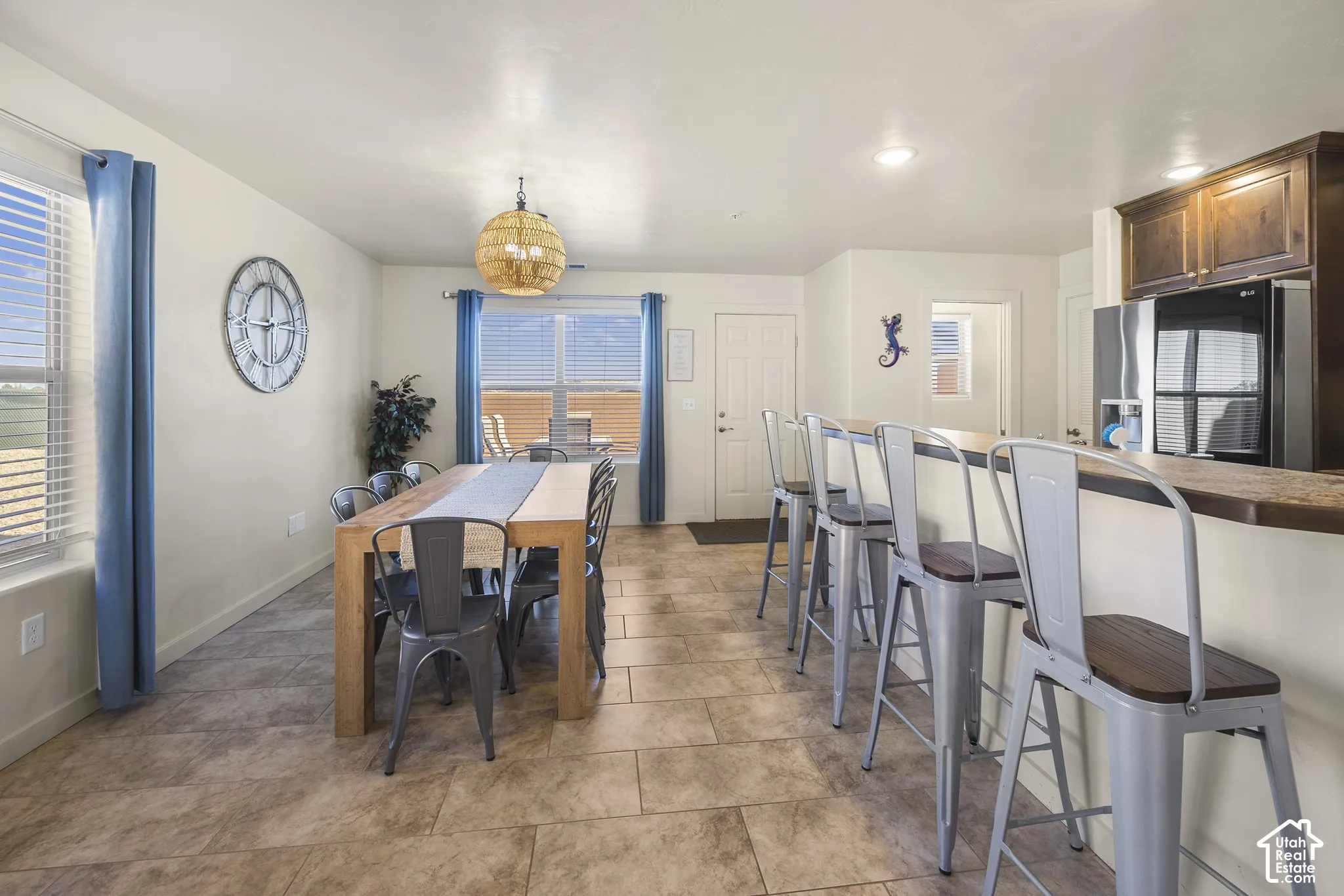 Open-concept kitchen and dining area featuring tile flooring, a breakfast bar with seating, dark wood cabinetry, and a dining area with a woven pendant light