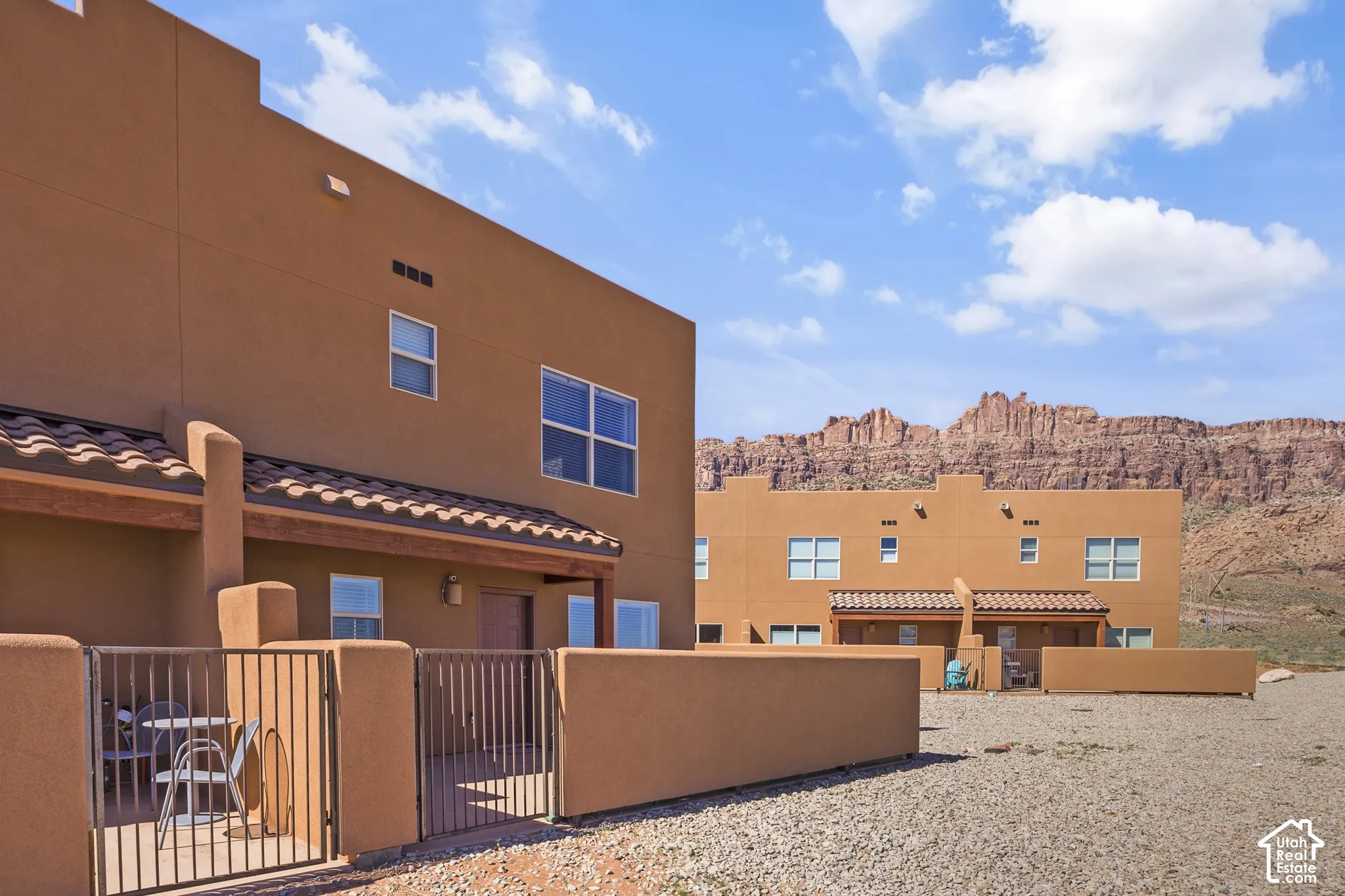 Stucco exterior with terracotta roof tiles, private gated patio, and surrounding mountainous terrain