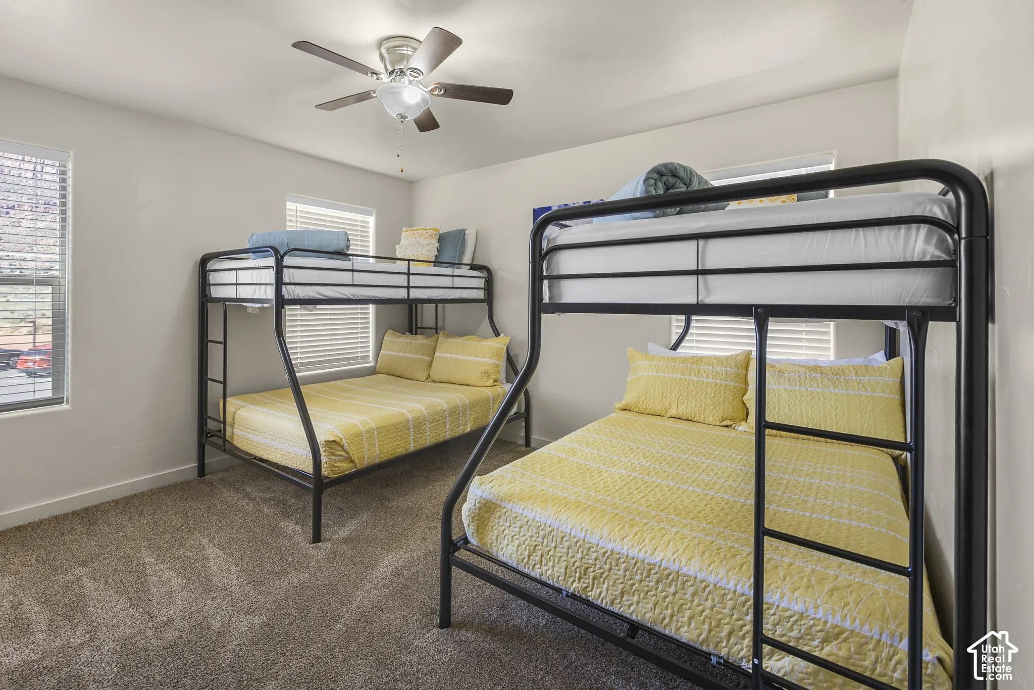 Carpeted flooring, multiple windows with blinds, and a ceiling fan with integrated lighting
