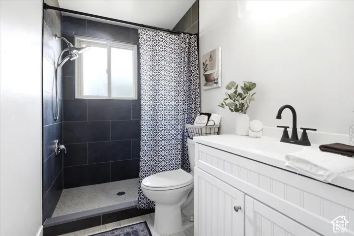 Walk-in shower with dark tile surround and a window