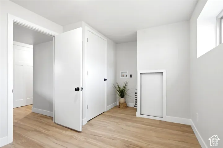 Bright utility space featuring wood-finish flooring, white walls, and a visible window