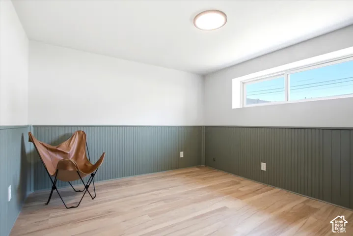 Wood-finish flooring, two-tone walls with beadboard paneling, and an egress window