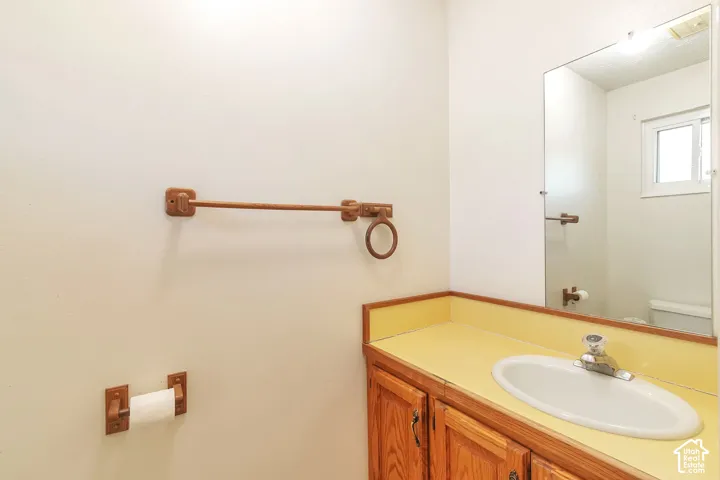 Wood-finish vanity with an integrated basin, yellow countertop, and a wall-mounted mirror