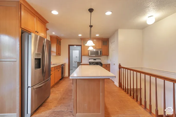 Kitchen featuring stainless steel appliances, wood-finish cabinetry, a central island, recessed lighting, and pendant lighting