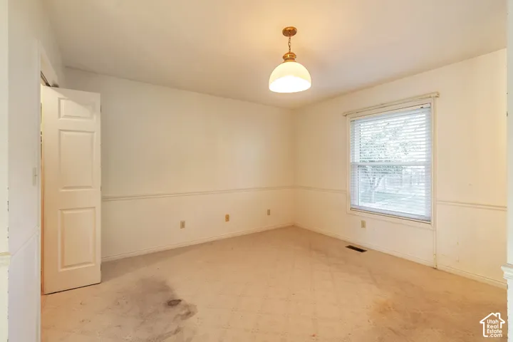 Neutral-toned walls, overhead lighting fixture, window with blinds, carpeted flooring, and a paneled door