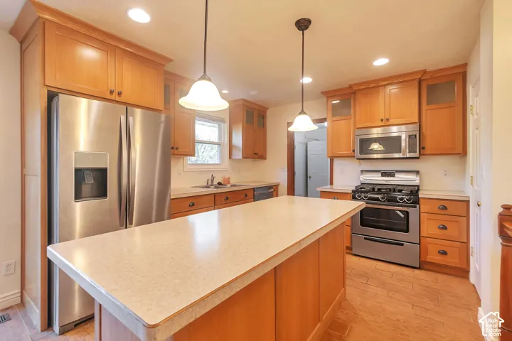 Kitchen featuring wood cabinetry, stainless steel appliances, a center island with a light-colored countertop, and recessed lighting