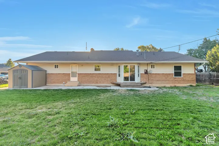 Expansive backyard with a concrete patio, brick and siding exterior, and a storage shed