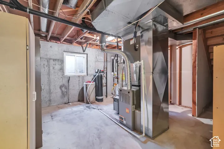 Unfinished basement space with exposed ceiling joists, concrete walls, a single window, and visible HVAC ductwork