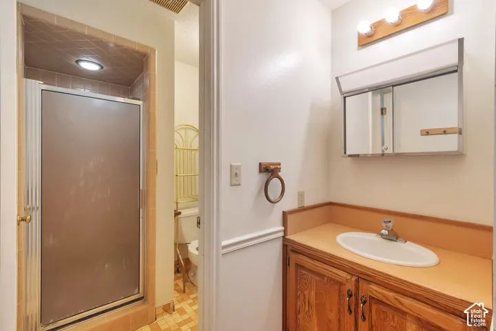 Bathroom featuring a wood-finish vanity with an integrated sink, wall-mounted medicine cabinet with mirror, and an adjacent shower enclosure with a frosted glass door