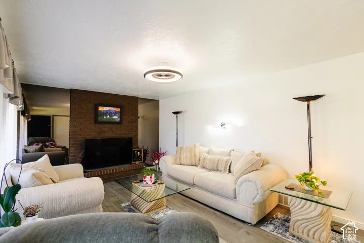 Brick accent wall with hearth, wood-finish flooring, and recessed ceiling lighting