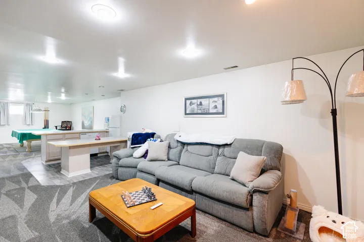 Expansive open-concept room featuring recessed lighting, a built-in bar with a light-toned countertop, wood-finish flooring, and a patterned area rug