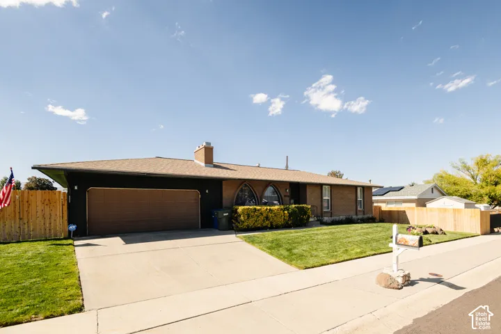 Brick and stucco exterior with a brown garage door, arched windows, and a mature hedge